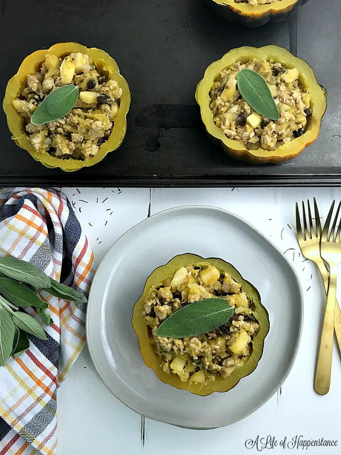 One turkey filled acorn squash on a white plate with the rest on a baking sheet. 