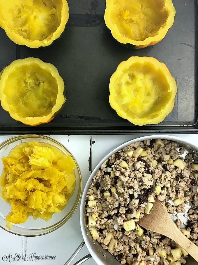 Hollowed out acorn squash with a pan filled with ground turkey. 