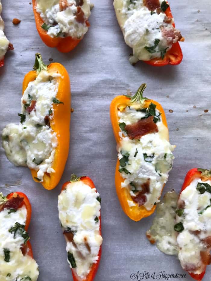 Cheese stuffed mini peppers with bacon on a baking sheet. 