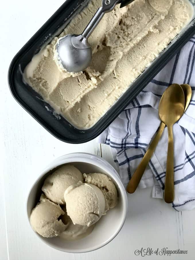 A loaf pan filled with no churn, dairy free vanilla cashew ice cream. There's a small bowl next to it filled with ice cream. 