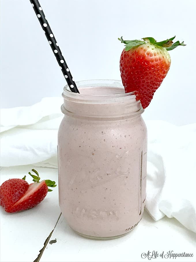 Strawberry shortcake smoothie in a mason jar garnished with a strawberry and straw. 