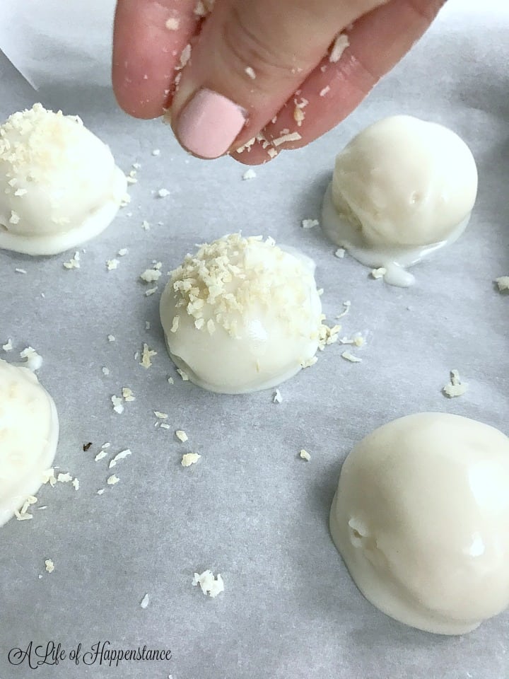 Sprinkling unsweetened shredded coconut on top of the coconut truffles. 