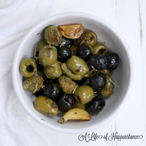 Roasted olives in a small white bowl.