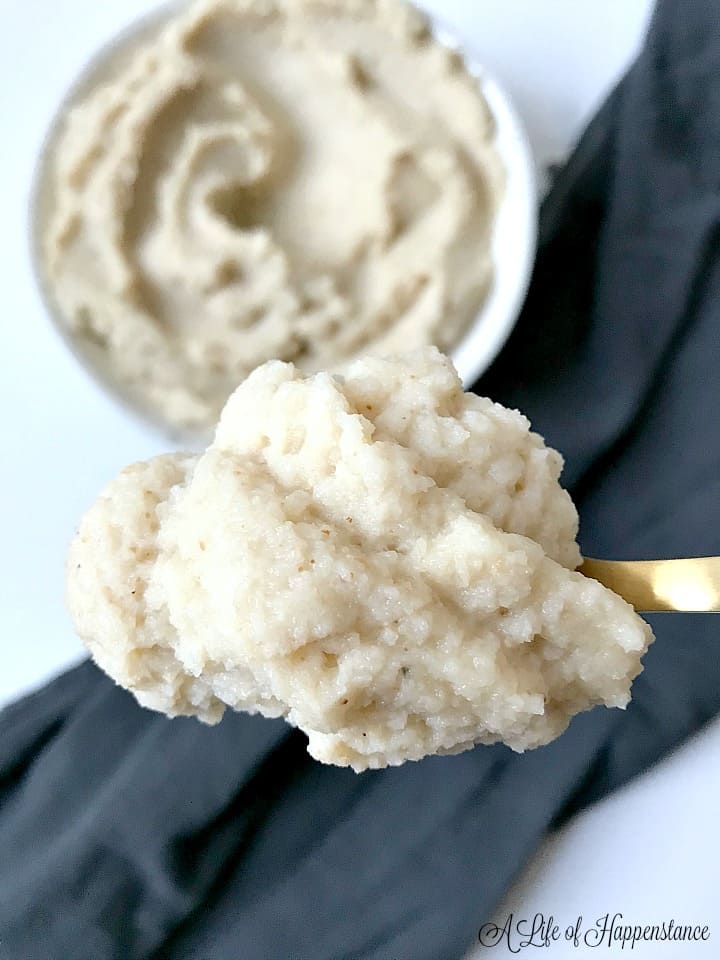 A spoonful of roasted mashed cauliflower with the rest of the side dish in the background. 