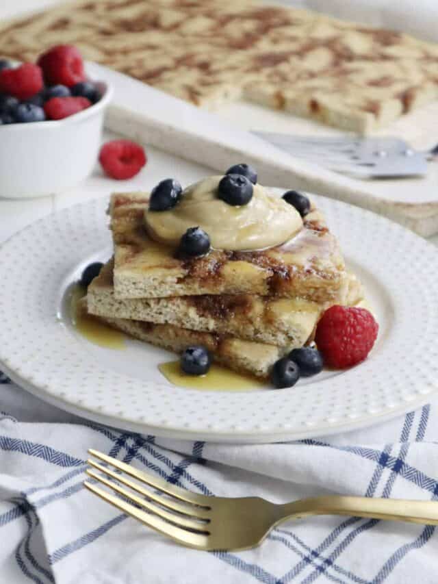 A stack of three pancakes topped with cashew cream, honey, and fresh berries.