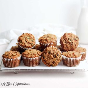 Healthy carrot zucchini muffins piled up on a cooling rack.