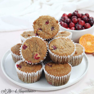 A stack of almond flour cranberry orange muffins on a white plate.