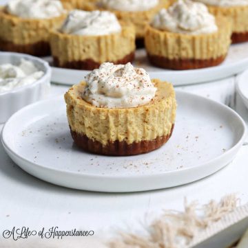 A gluten free mini pumpkin cheesecake topped with cashew cream on a white plate.