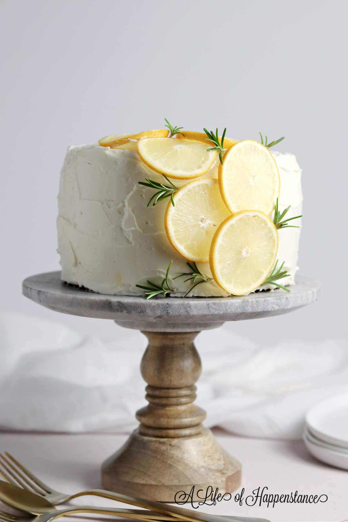 The lemon rosemary cake on a cake stand.