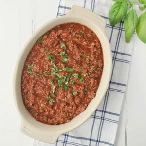 Meat sauce garnished with fresh basil in an oval serving dish.