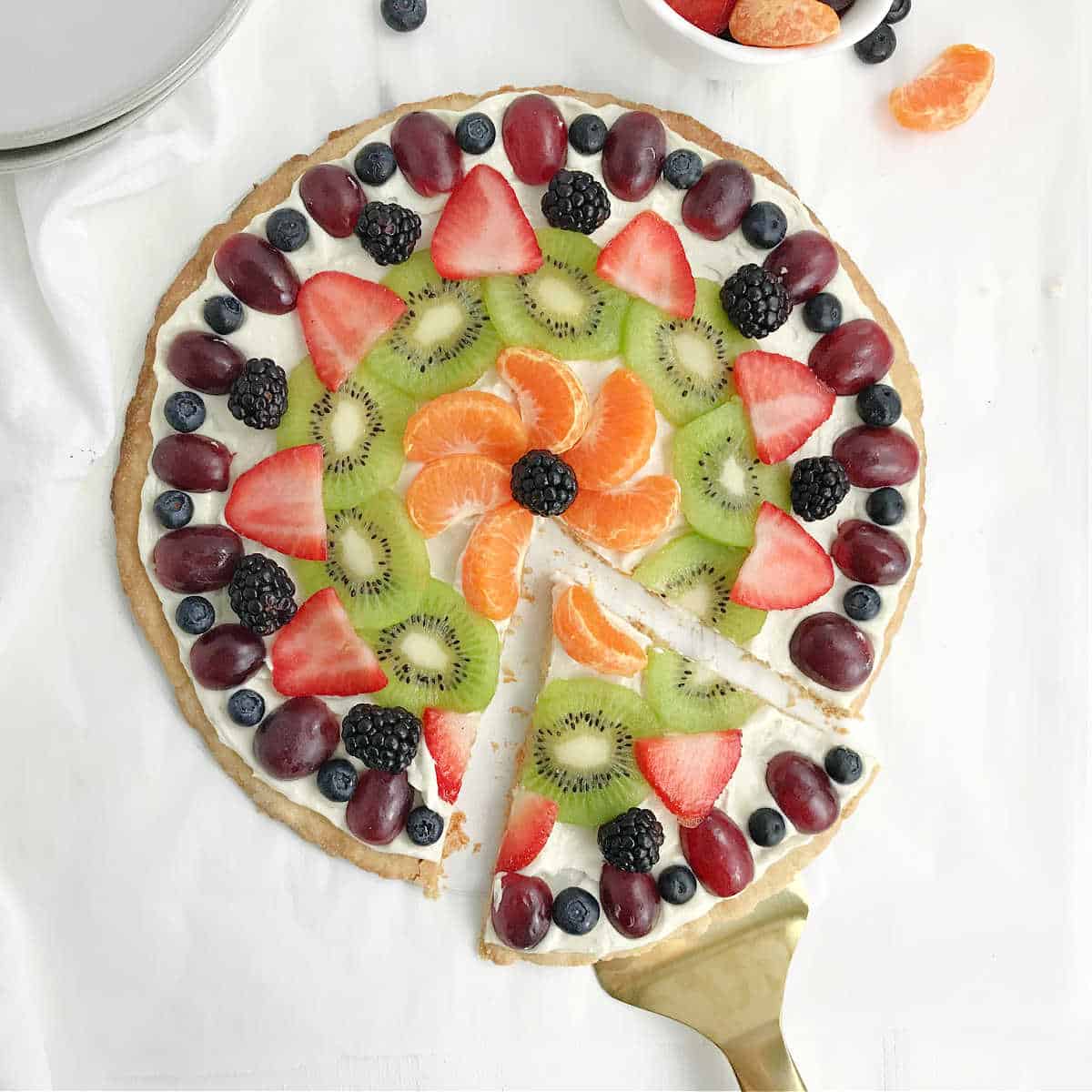 A slice of fruit pizza being removed with a spatula.