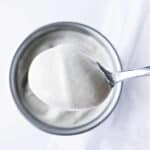 A spoonful of cream with a silver bowl of more cream in the background.
