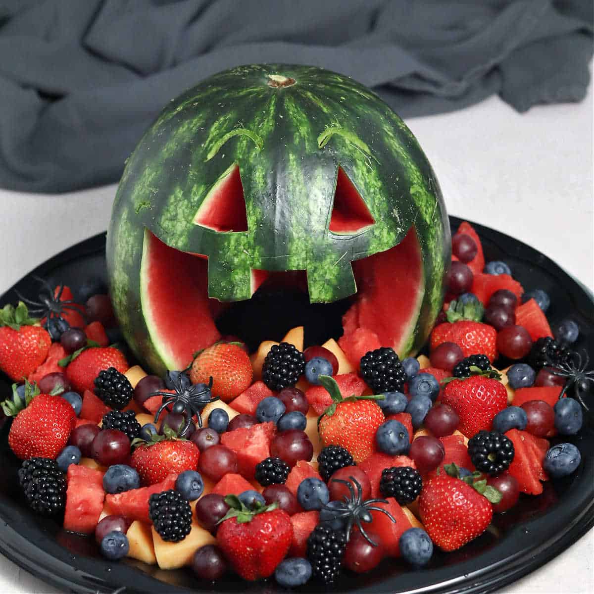 Fruit salad coming out of a watermelon jack-o-lantern.